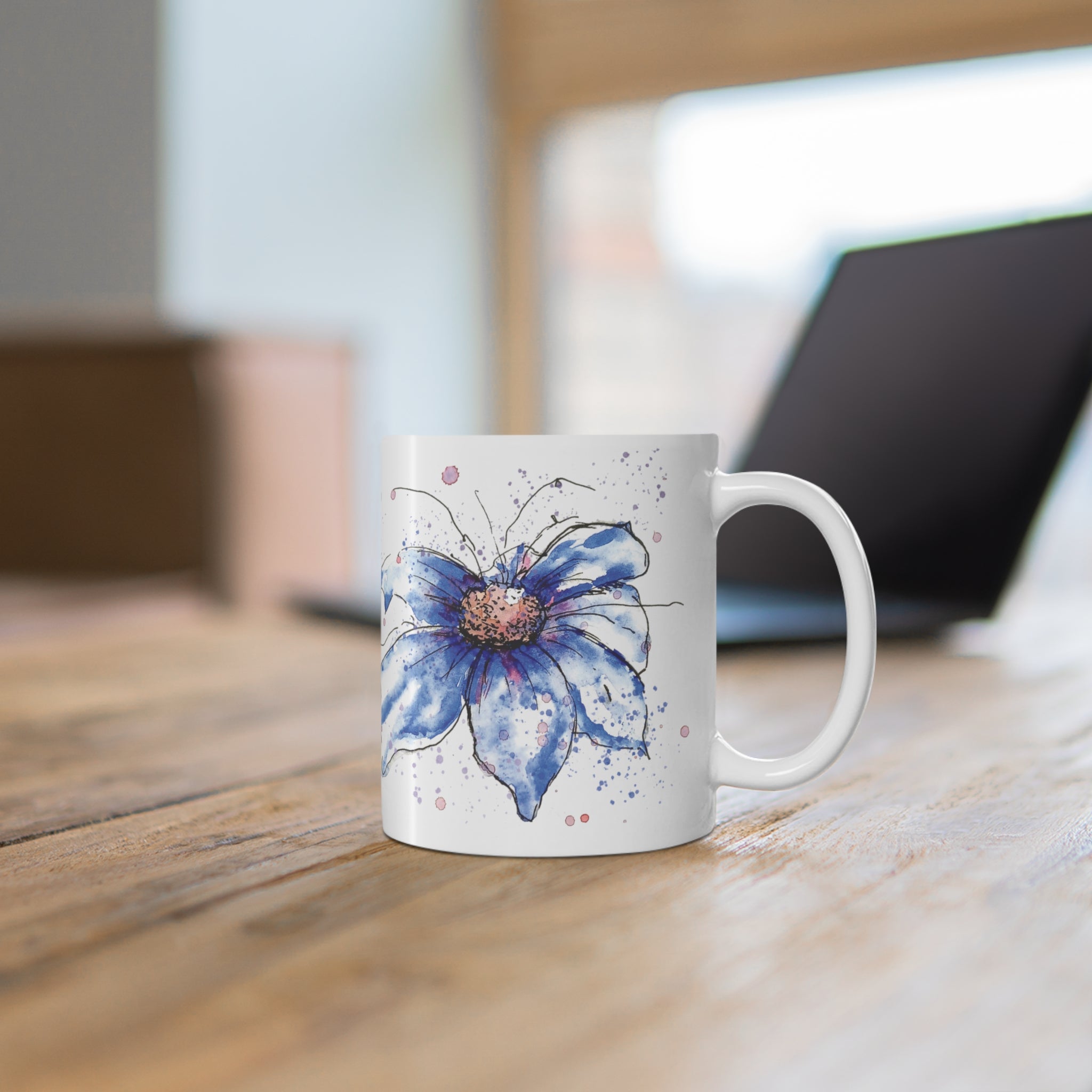 Blue cosmos floral mug on wooden desk in home office workspace setting
