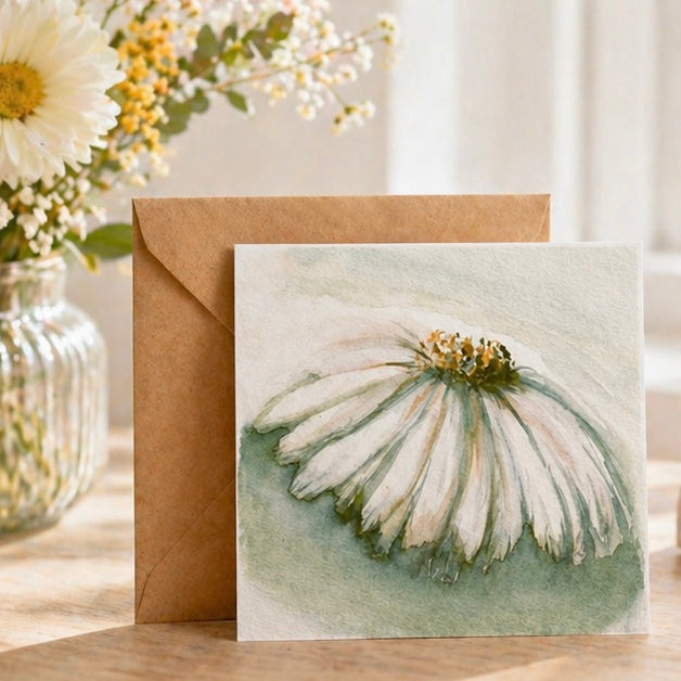 Greeting card with floral design on a wooden surface with flowers and books in the background
