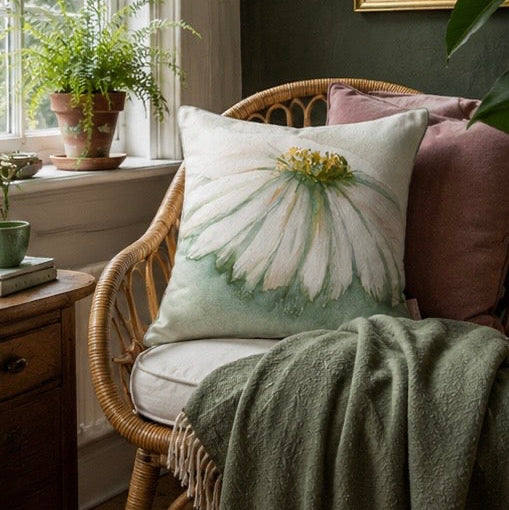 Decorative pillow with floral design on a wicker chair in a cozy room.