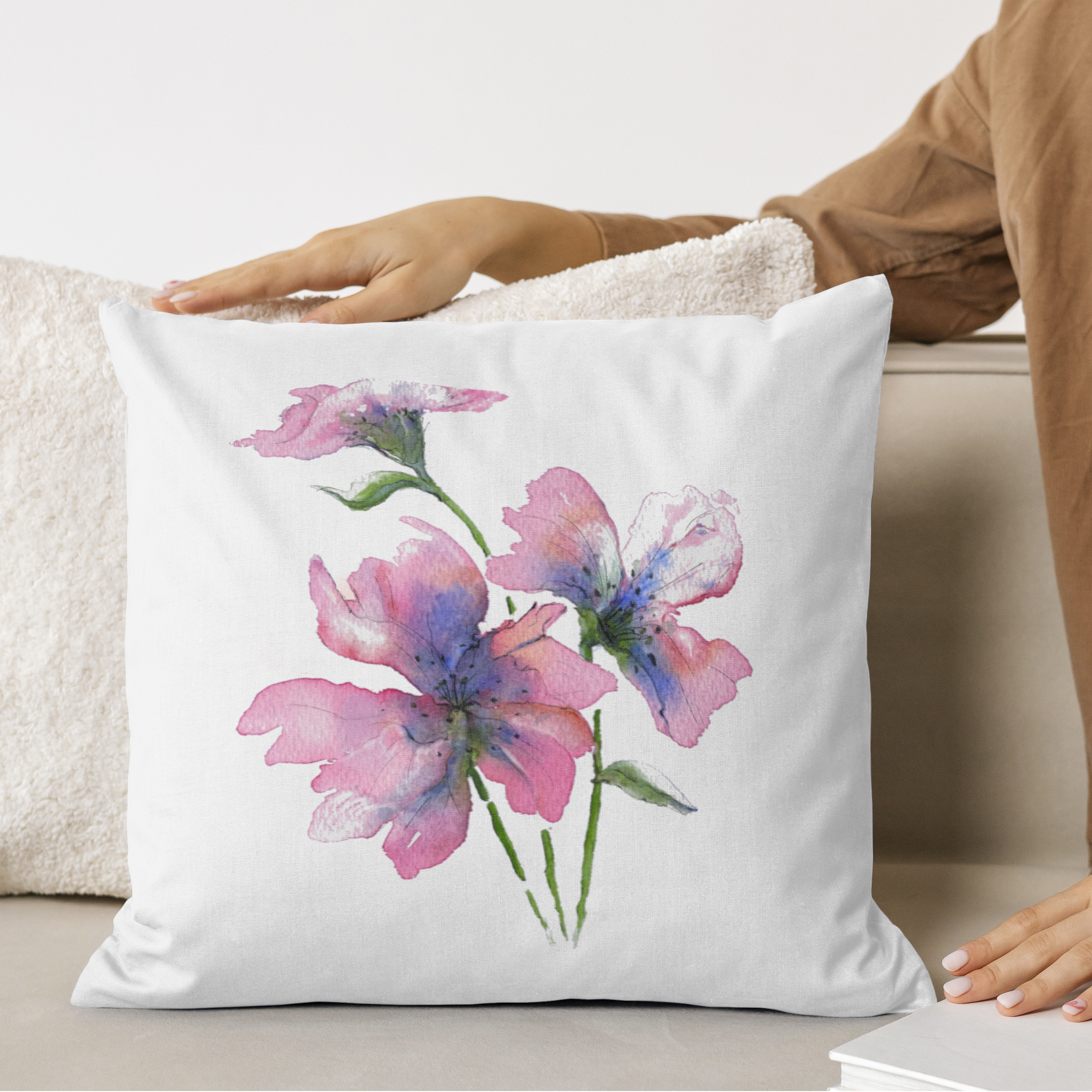 Pink floral linen cushion with person touching, on a sofa