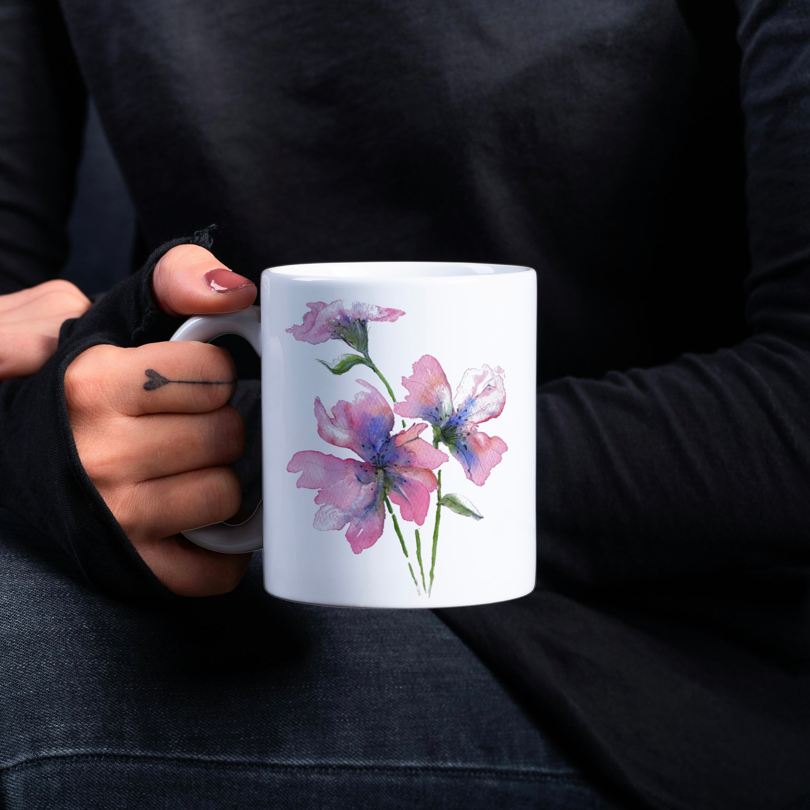 Person holding a mug with floral design against a dark background