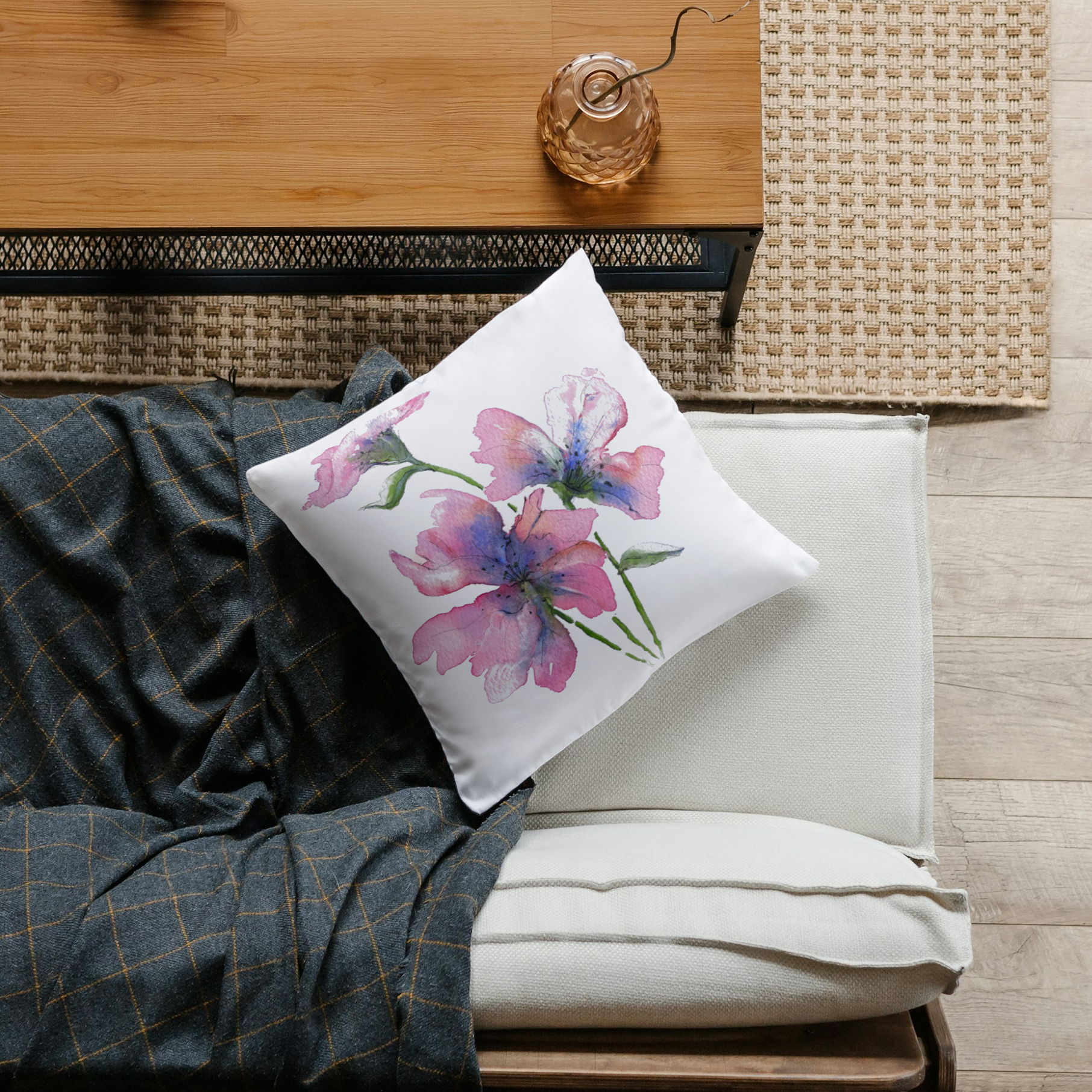 Watercolour pink and blue flower pillow from above on a white sofa and check grey throw