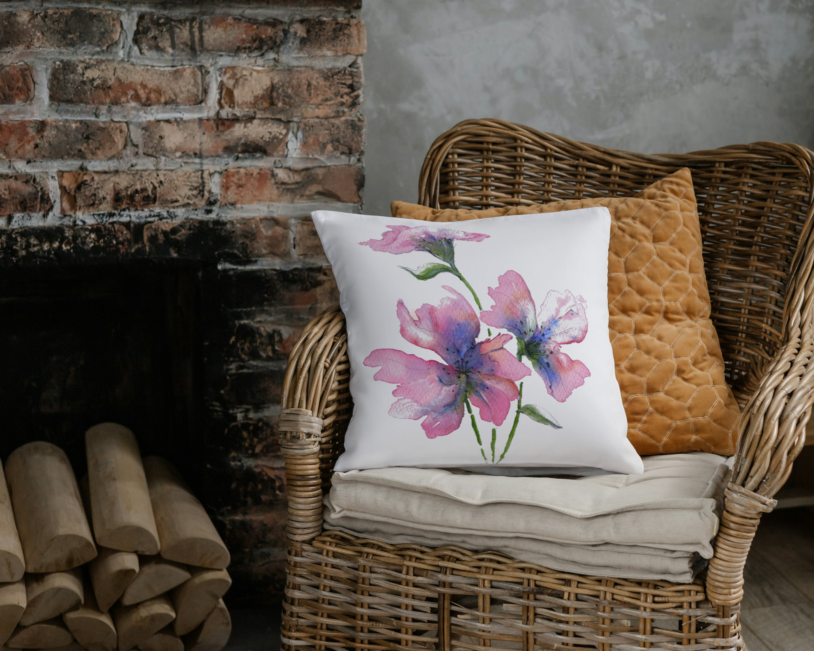 Decorative pillow with floral design on a wicker chair against a brick wall.